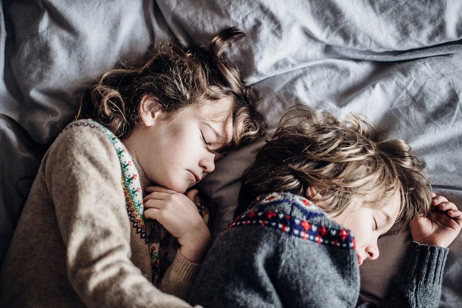 Two children sleeping with sweaters on