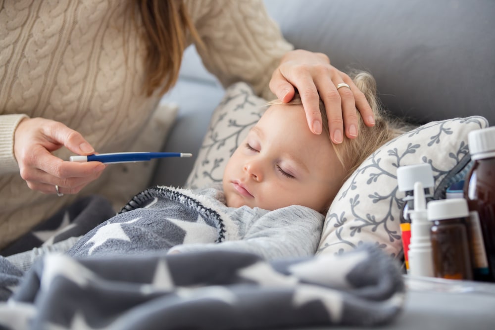 Mother checks sick child’s temperature who has an autoimmune disorder