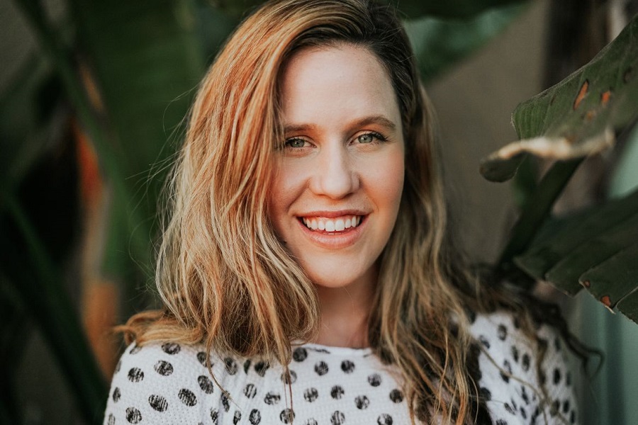 Woman smiling surrounded by green leaves