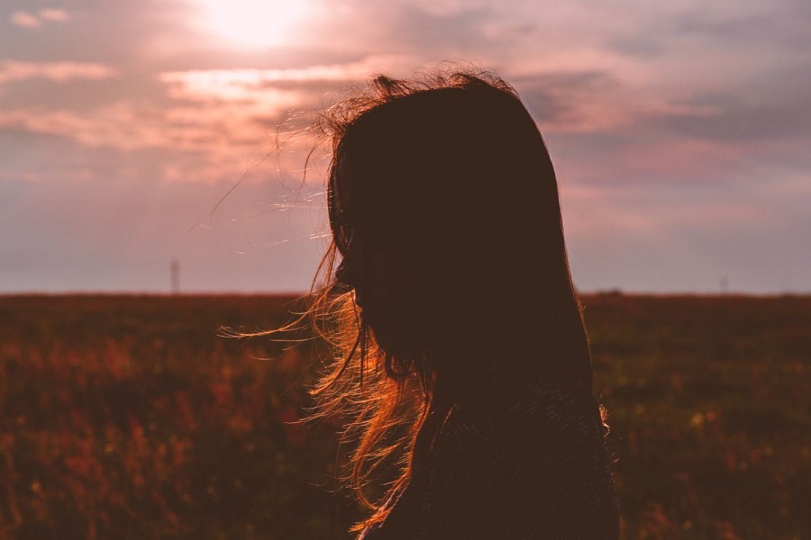 Girl standing in a cornfield during sunset