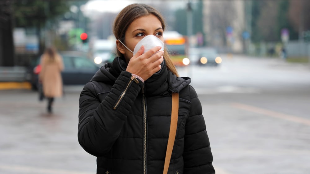 Woman with long haul COVID walking and wearing a mask.