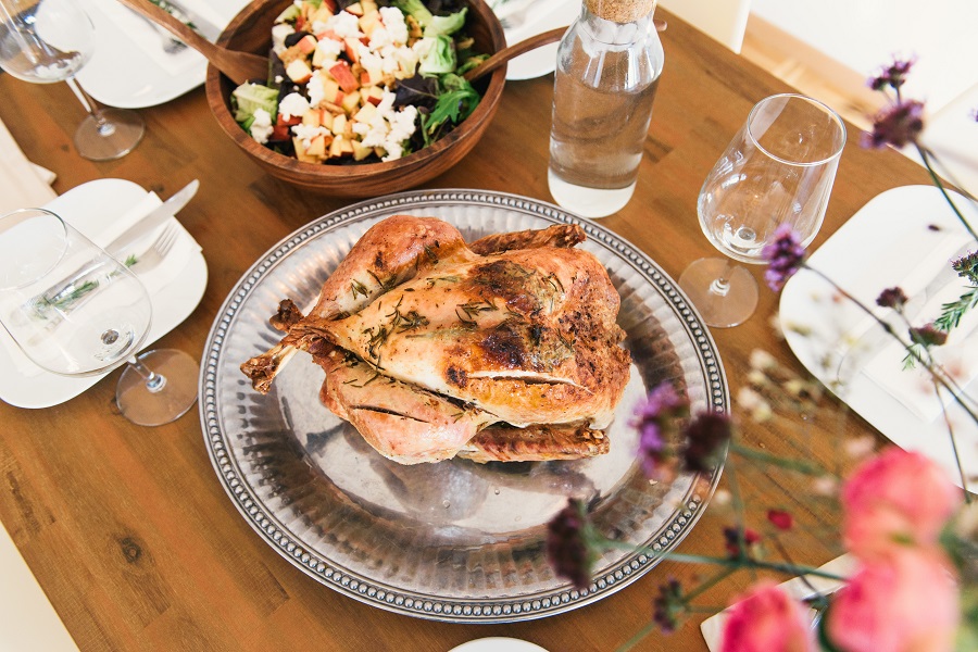 Turkey on a silver platter next to a wooden salad bowl