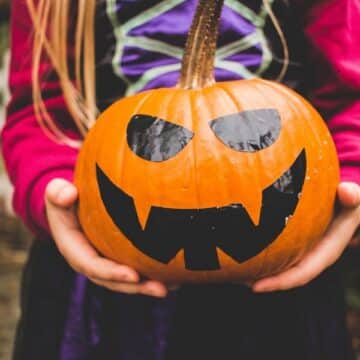 Young girl in a costume holding a jack o lantern