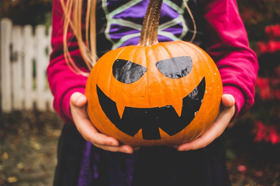 Young girl in a costume holding a jack o lantern