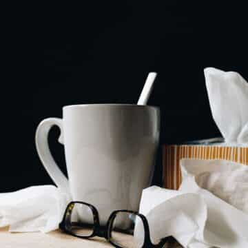 Ceramic mug surrounded by a tissue box, tissues and glasses