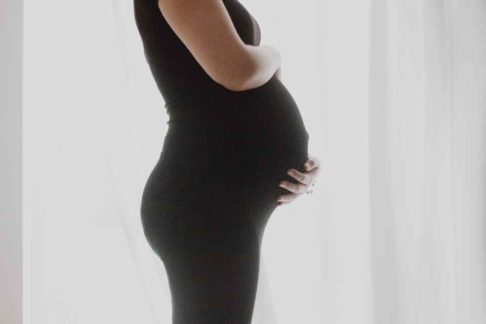 Woman in all black touching her pregnant stomach