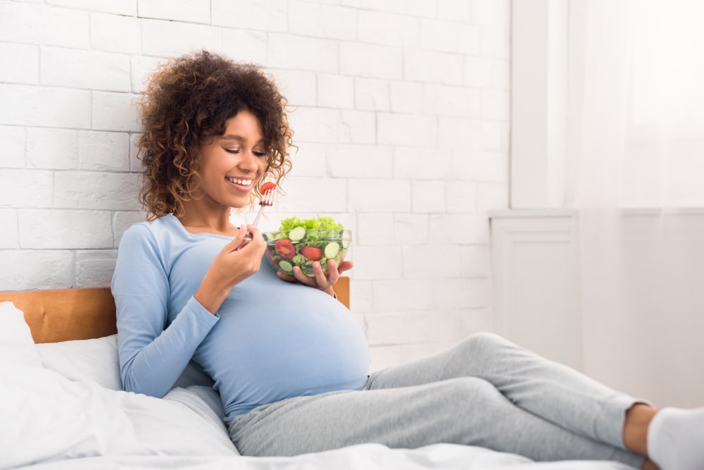 Woman eating nutritious salad while pregnant