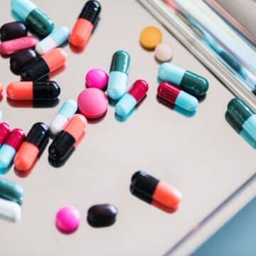 A handful of colorful pills on a silver tray