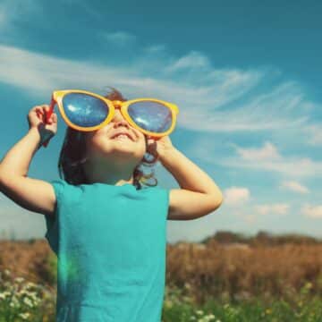 little kid looking at the sky through a pair of giant sunglasses
