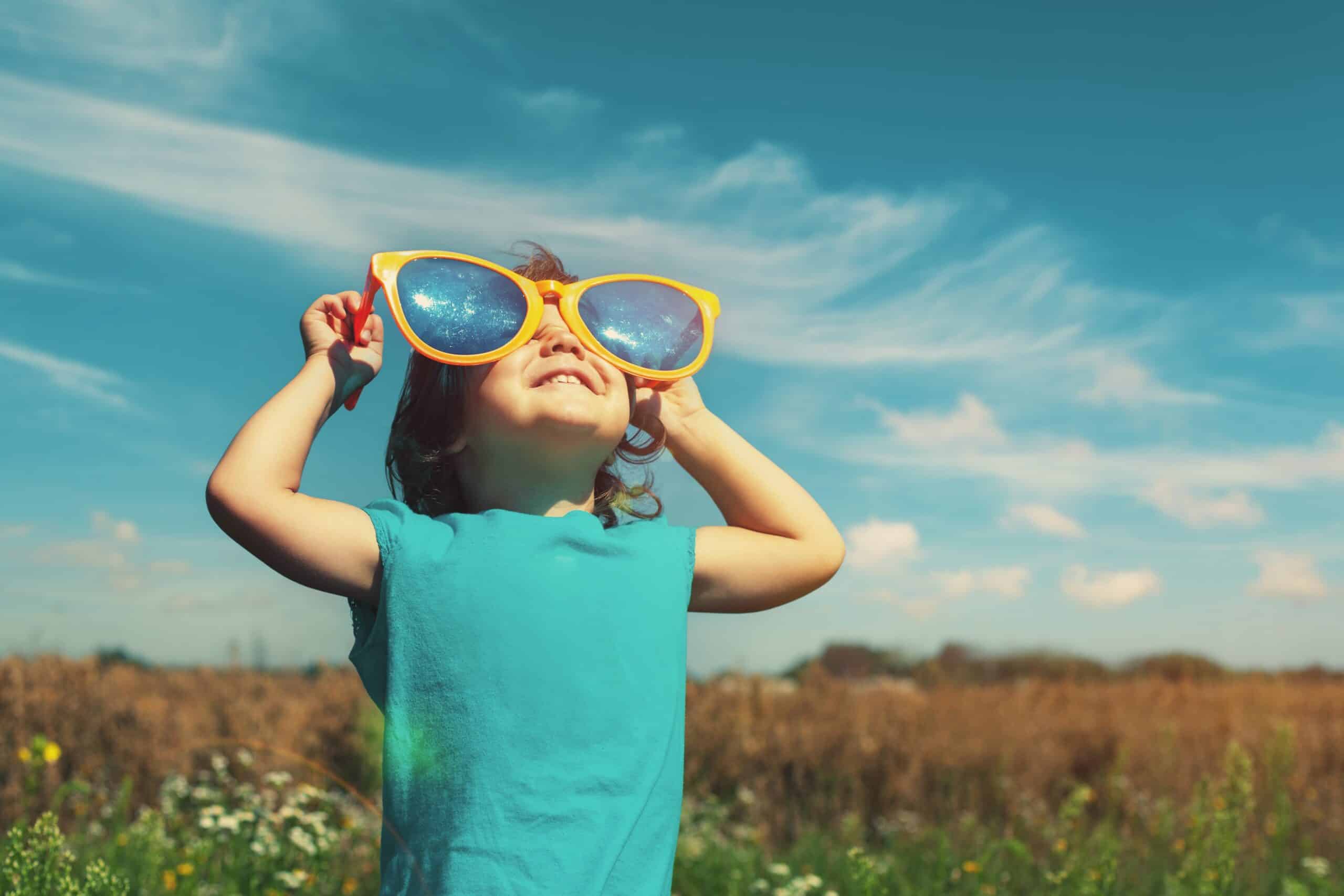 little kid looking at the sky through a pair of giant sunglasses